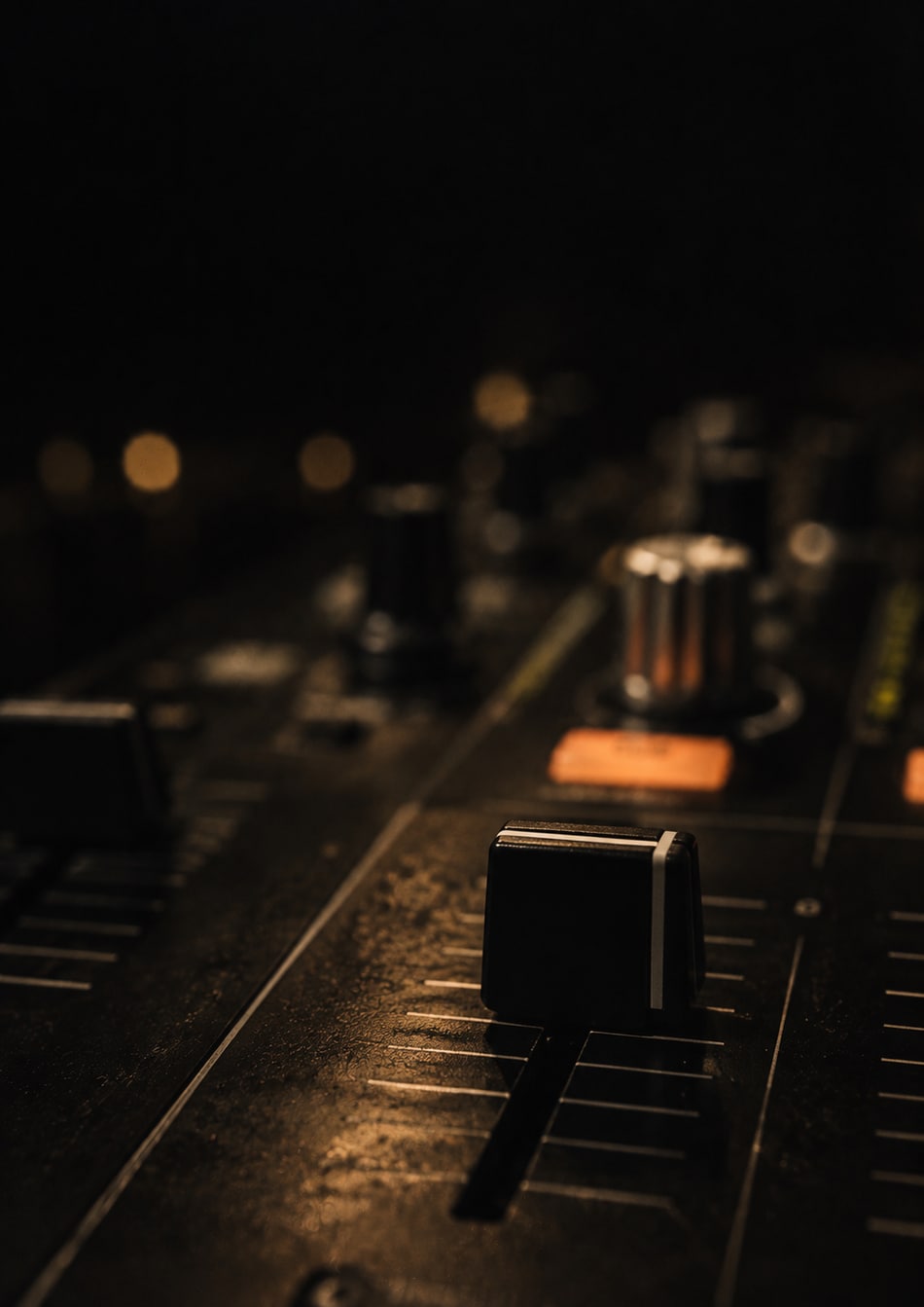 A channel fader in focus on a dark DJ mixer with gold highlights, artwork from the toolkit chapter
