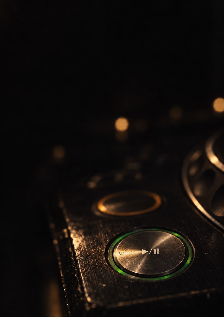 Close-up of a CDJ play and pause button with a green ring and warm gold light, artwork from Beyond the Mix