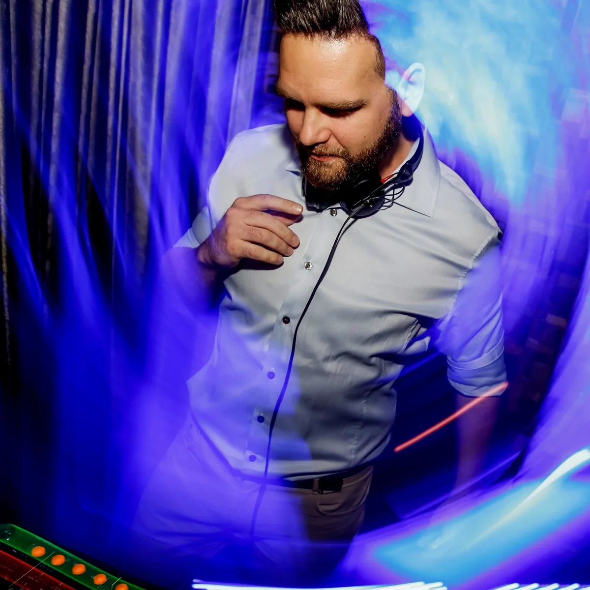 Sean wearing headphones around his neck at Blackbird in 2015, surrounded by blue club lighting.