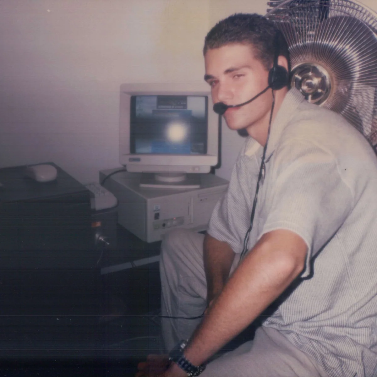Sean at his computer in Brisbane in 1998, wearing a headset beside a CRT monitor.